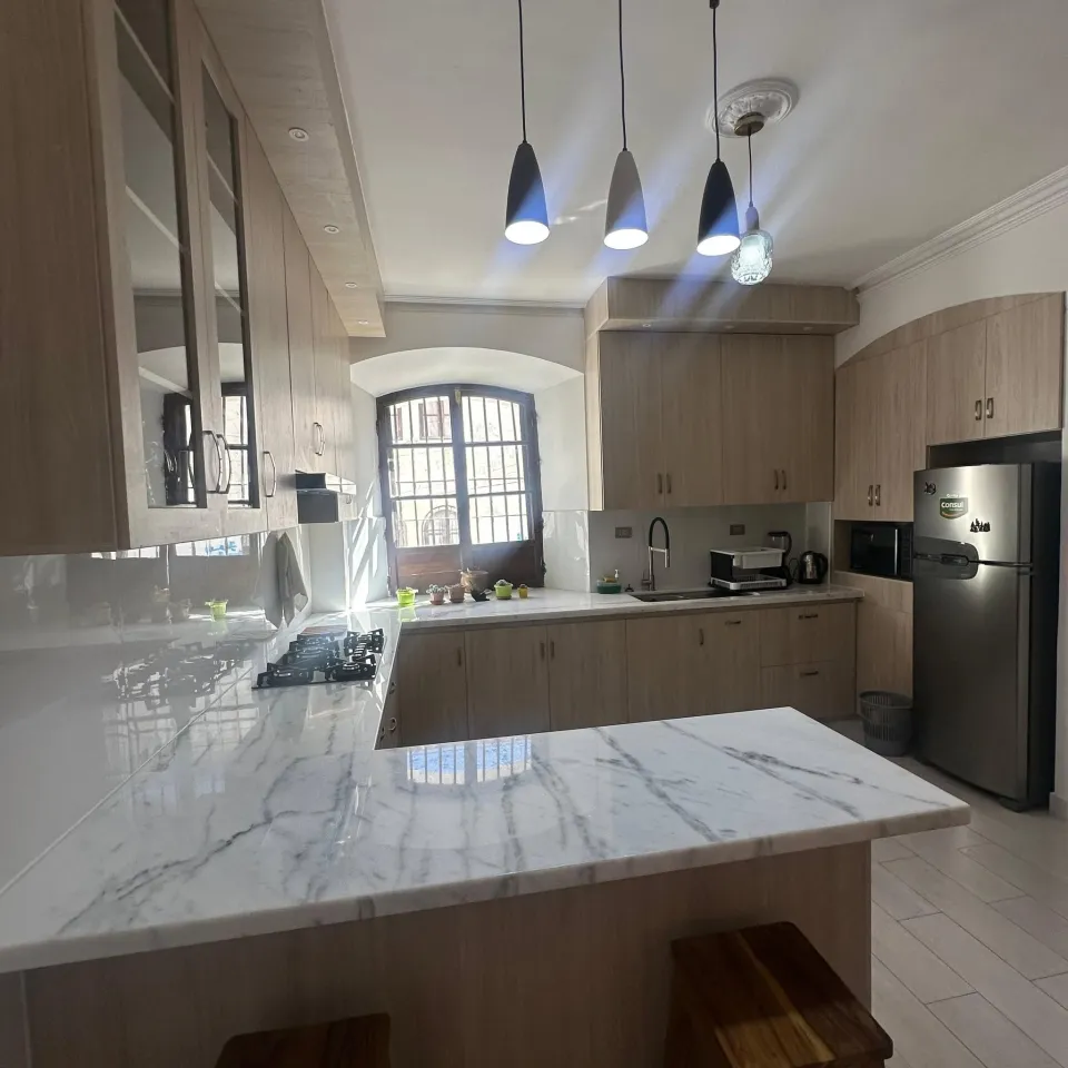 Cocina con mesón de mármol y cajonería alta y baja