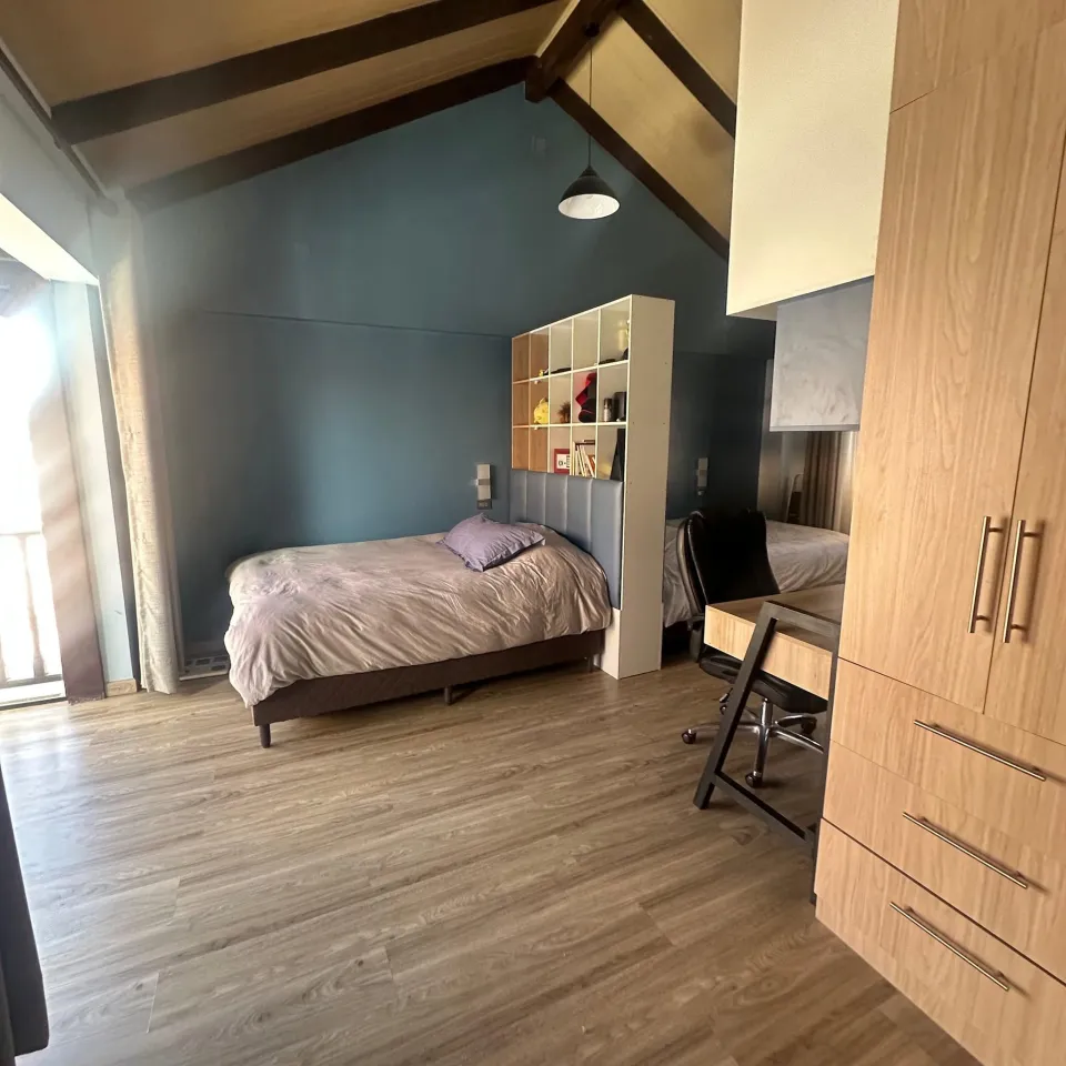 Dormitorio con escritorio y techo de madera