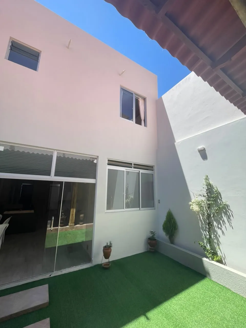 Patio con césped sintético y ventanales